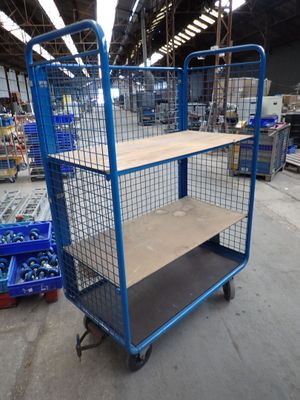 a blue cart with a shelf in the middle of a warehouse