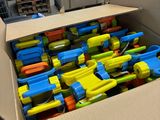 une boîte en carton remplie d'une multitude de pistolets jouets de toutes les couleurs