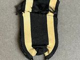 an iron cross with a black and yellow ribbon on a gray surface