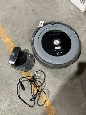 une photo d'un Roombake posé par terre à côté d'un chargeur