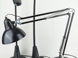 deux lampes de bureau noires posées sur une surface blanche, avec un fond blanc