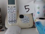 many items on a shelf that include a cell phone, a cup of coffee, and a bottle of beer