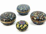 four small round boxes with floral designs on them sitting on a white surface