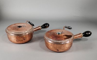 une paire de casseroles et poêles anciennes en cuivre avec des poignées noires
