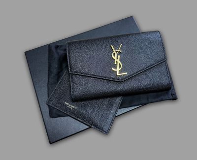 a close up of a black wallet with a gold ysl logo on it