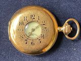 a gold pocket watch sitting on a blue surface