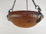 a wooden bowl hanging from a chain on a wall