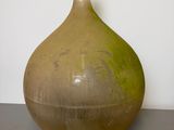 a brown vase sitting on a table with a white wall in the background