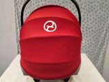 a baby car seat with a red cover on top of it