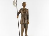 a wooden statue of a man holding a spear and a flag