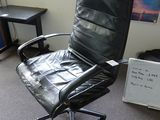 une chaise de bureau en cuir noir dans un coin de la pièce