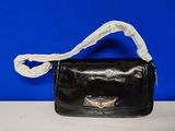 un sac à main noir avec une anse blanche posé sur une table