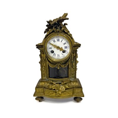 une horloge en or surmontée d'un oiseau