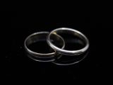 two wedding rings on a black surface with reflection