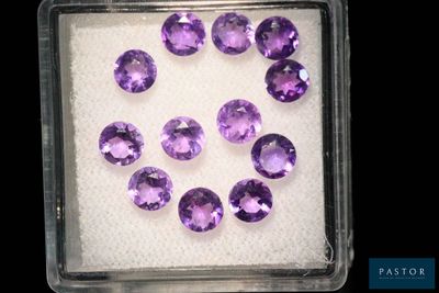 un gros plan sur un tas de pierres précieuses violettes dans un récipient en plastique