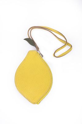 un sac à main en forme de citron muni d'une lanière en cuir, sur fond blanc