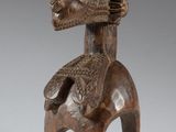 an image of a wooden statue of a woman with a bird on her back