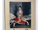 an old photo of a woman sitting on a bed in a room