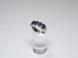 a close up of a ring with blue stones on a white surface
