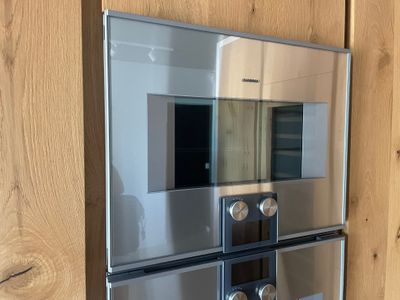une photo d'un four en acier inoxydable fixé à un mur en bois