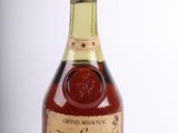 une photo d'une bouteille de brandy posée sur une surface blanche