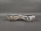 two cups with birds and flowers on them sitting on a table