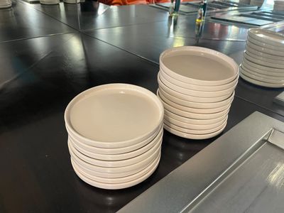 il y a beaucoup d'assiettes blanches sur le plan de travail de la cuisine