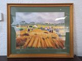 painting of people working in a field in a frame on a table