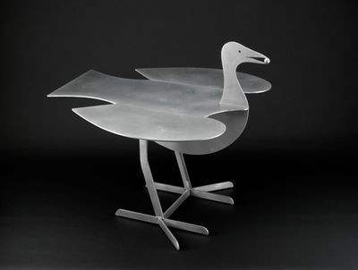 a metal bird that is sitting on a metal stand