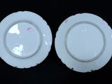 pair of white porcelain plates with pink flowers on them on a black surface