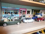 Des petites voitures sont alignées sur une étagère devant un magasin
