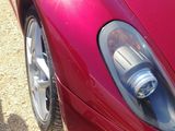 a red sports car parked in a gravel lot