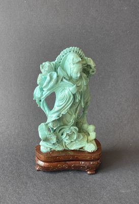statue d'une femme tenant un poisson, posée sur un socle, sur fond gris