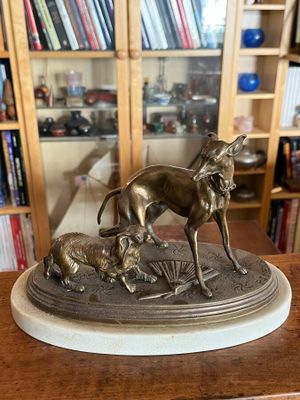 statue représentant un chien et un chat posée sur une table devant une bibliothèque