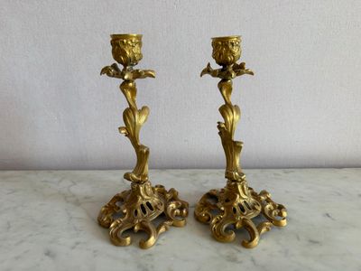 une paire de bougeoirs anciens en laiton posés sur une table en marbre