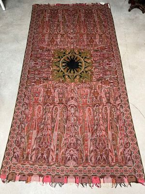 rug on the floor in a room with a chair and a table in the background