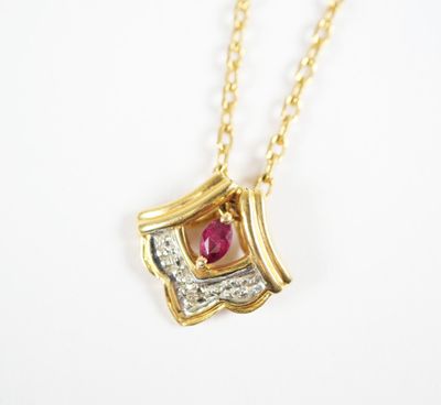 a close up of a gold necklace with a ruby and diamond pendant