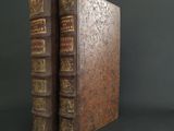two old books are sitting side by side on a black surface