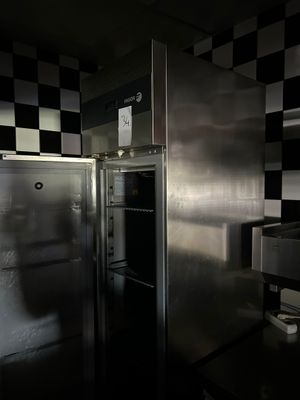 cuisine faiblement éclairée, équipée d'appareils électroménagers en inox et dont les murs sont recouverts d'un motif à carreaux