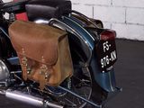 a motorcycle parked in a parking lot with a bag on the back of it