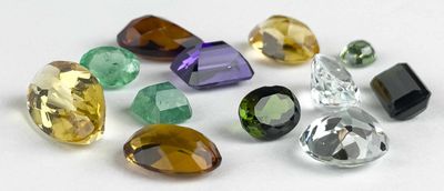 Plusieurs pierres précieuses de différentes couleurs sont disposées sur une surface blanche.