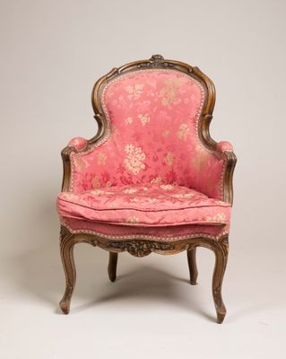 une vieille chaise dont l'assise est recouverte d'un tissu rose