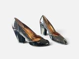 une paire d'escarpins noirs et argentés posés sur une surface blanche