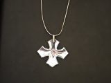 un gros plan d'un pendentif en forme de croix suspendu à une chaîne, posé sur une surface noire
