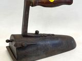 an old iron with a wooden handle on a white surface