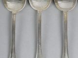five spoons are lined up in a row on a gray surface