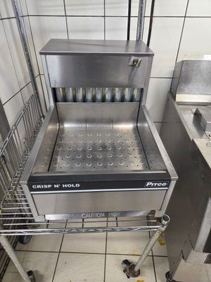 une petite friteuse professionnelle dans une cuisine où il y a beaucoup de nourriture