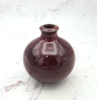 un petit vase rouge posé sur un plan de travail en marbre