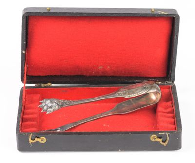 une cuillère ancienne en argent et son repose-cuillère, présentés dans une boîte rouge