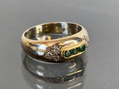 a close up of a gold ring with green stones on it